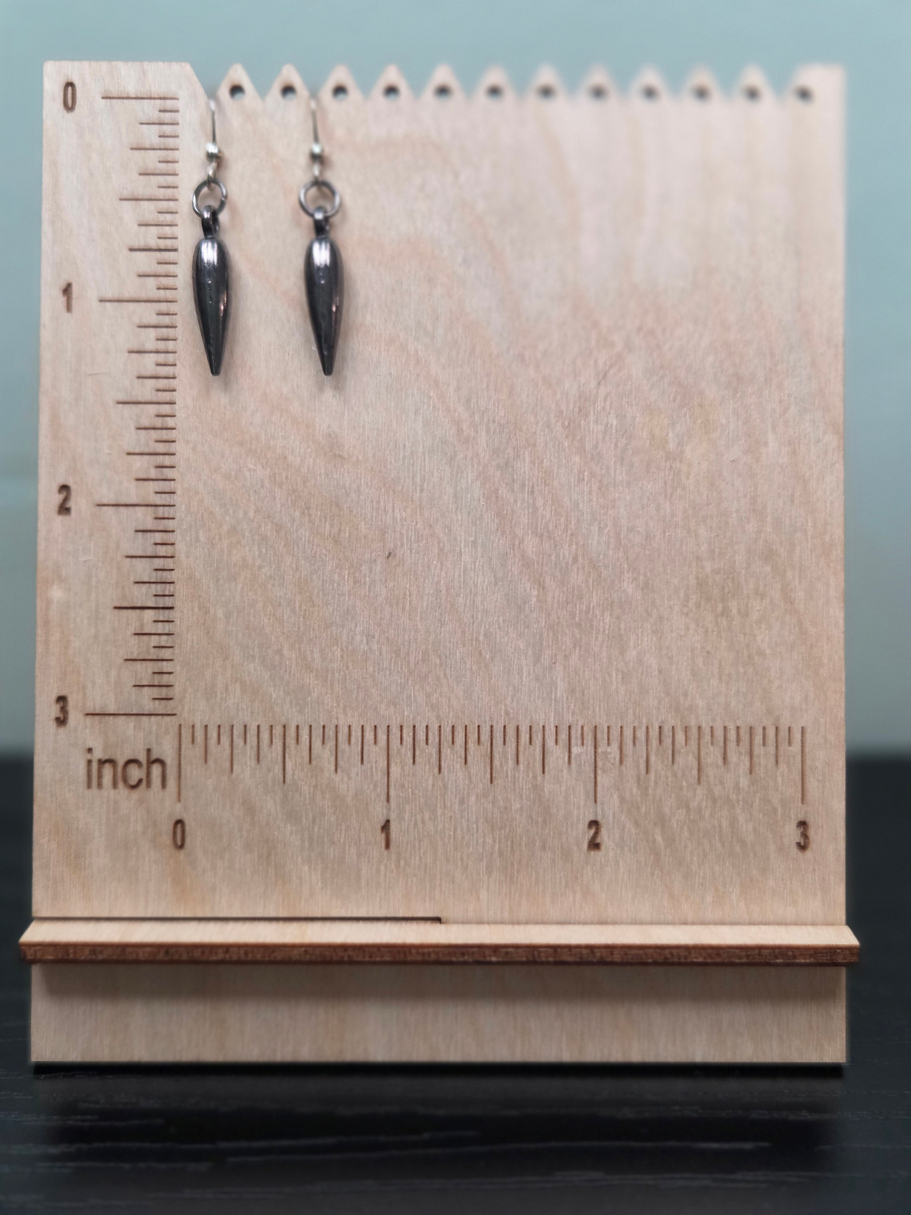Gunmetal teardrop spike charm dangle earrings against ruler showing approximately 1 inch length